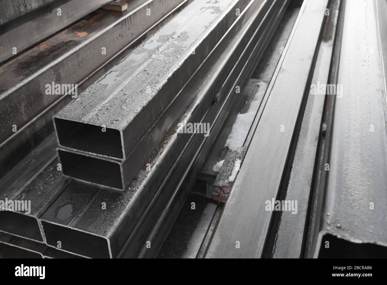 Stapel gewalzter Metallprodukte, graue Stahlrohre mit rechteckigem Querschnitt, Nahaufnahme mit selektivem Weichfokus Stockfoto