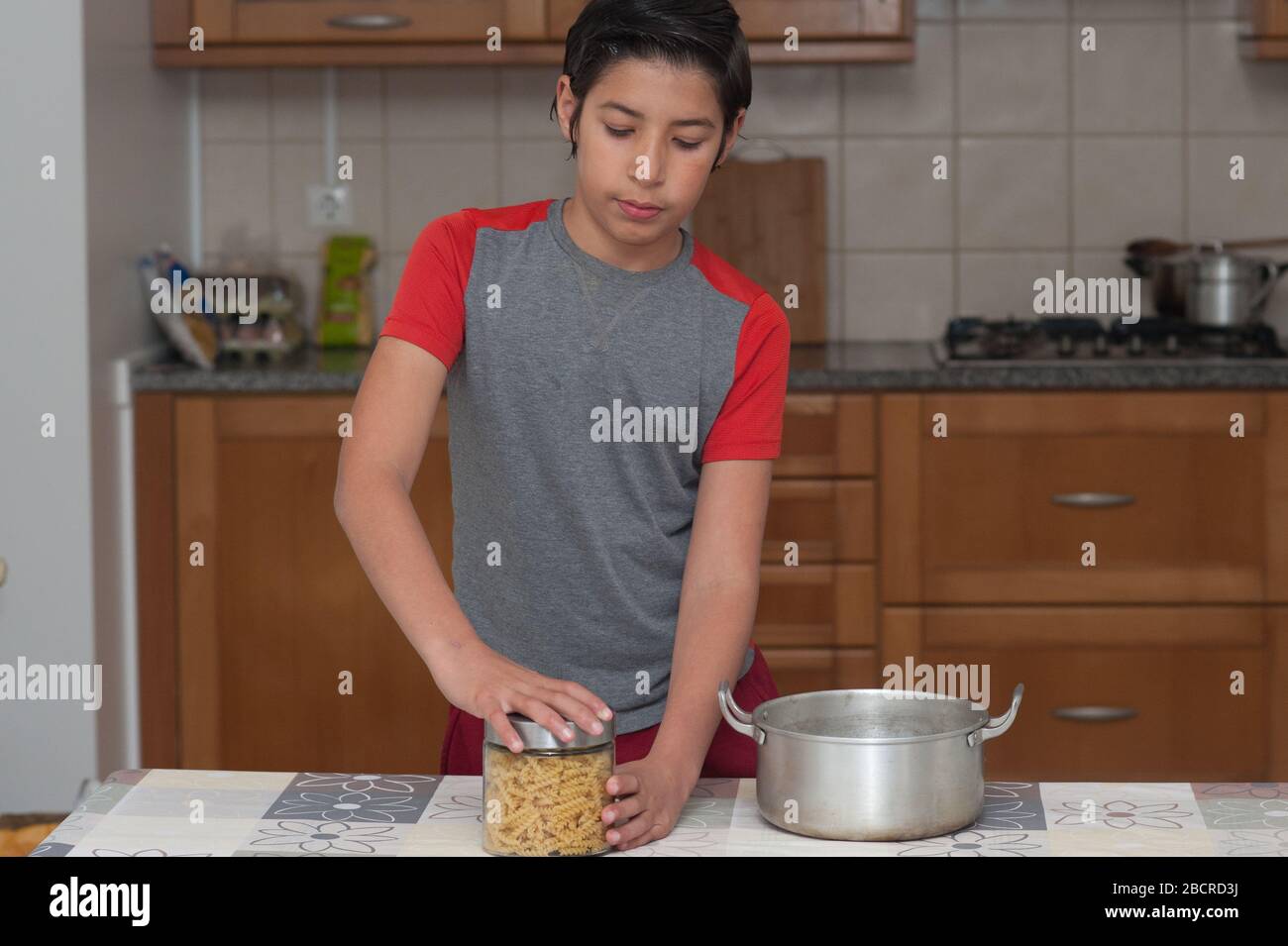 Junge, die eine Flasche Pasta in der Küche öffnet. Bild mit einem schönen Kopierraum. Stockfoto