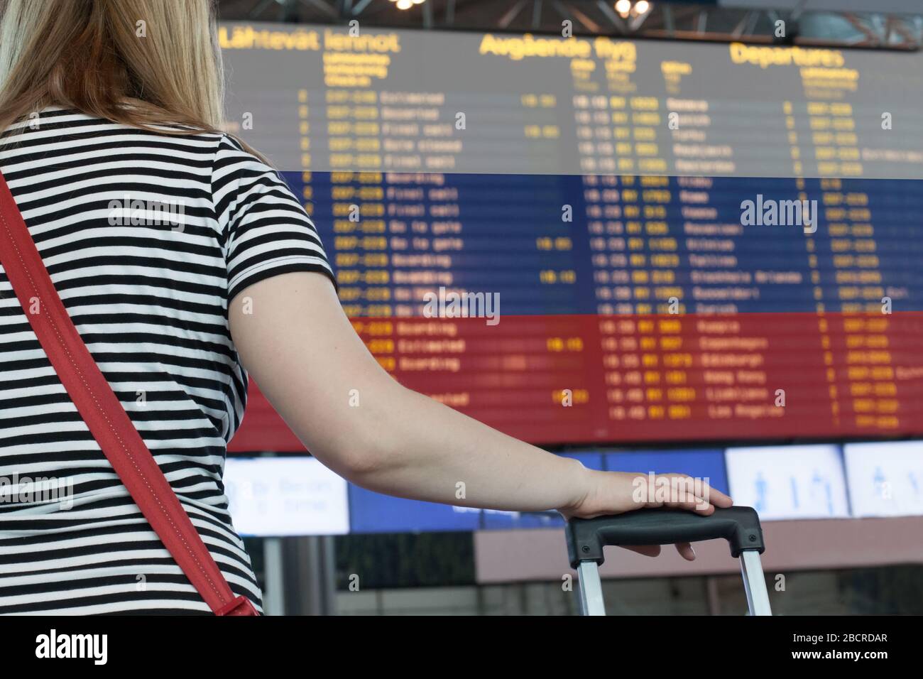 Frau schaut auf die Anzeigetafel am Flughafen. Wählen Sie ein Land für Reisen oder Migration aus. Stockfoto