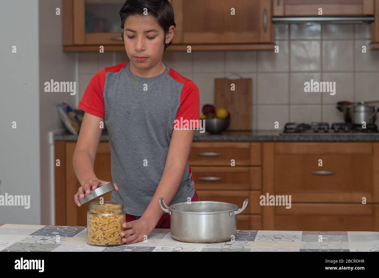 Junge, die eine Flasche Pasta in der Küche öffnet. Bild mit einem schönen Kopierraum. Stockfoto