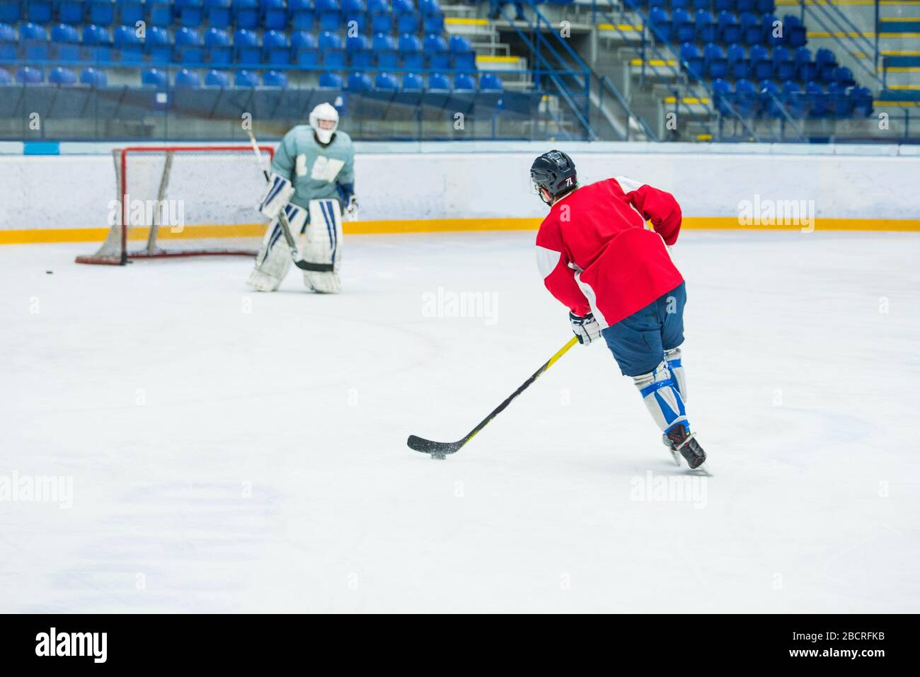 Eishockeyspieler auf dem Eis, professionelles Eishockeyspiel, Sportfoto, Torwart im Hintergrund Stockfoto