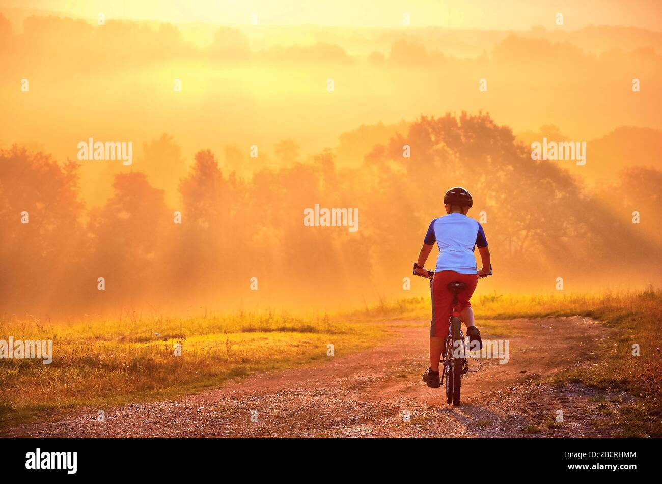 Junger Mann auf Fahrradtour in wunderschöner Sonnenaufgangs-Natur. Stockfoto