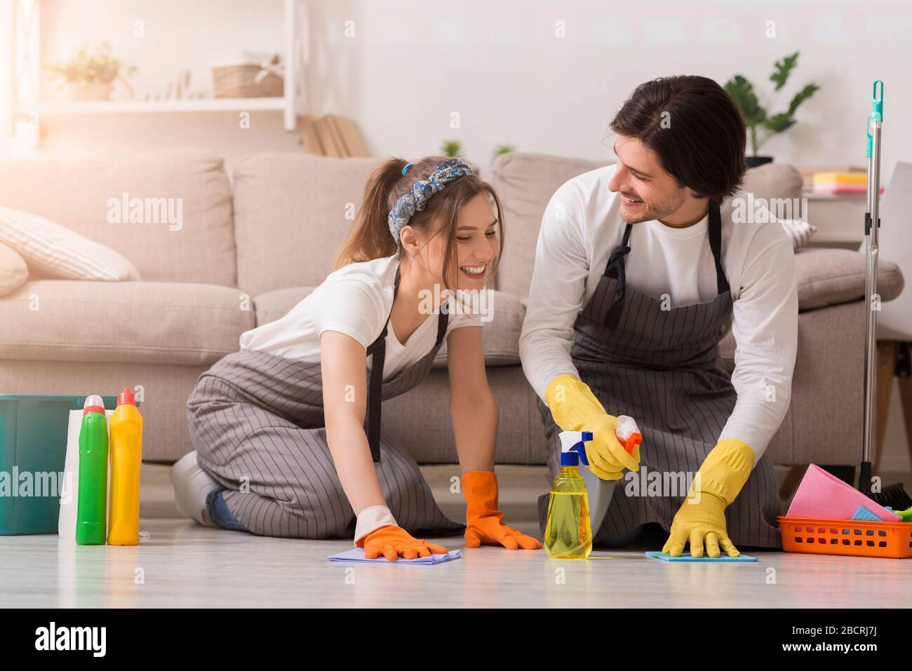 Häusliche Reinigung. Glückliche, tausendjährige Paare, die gemeinsam den Boden waschen Stockfoto