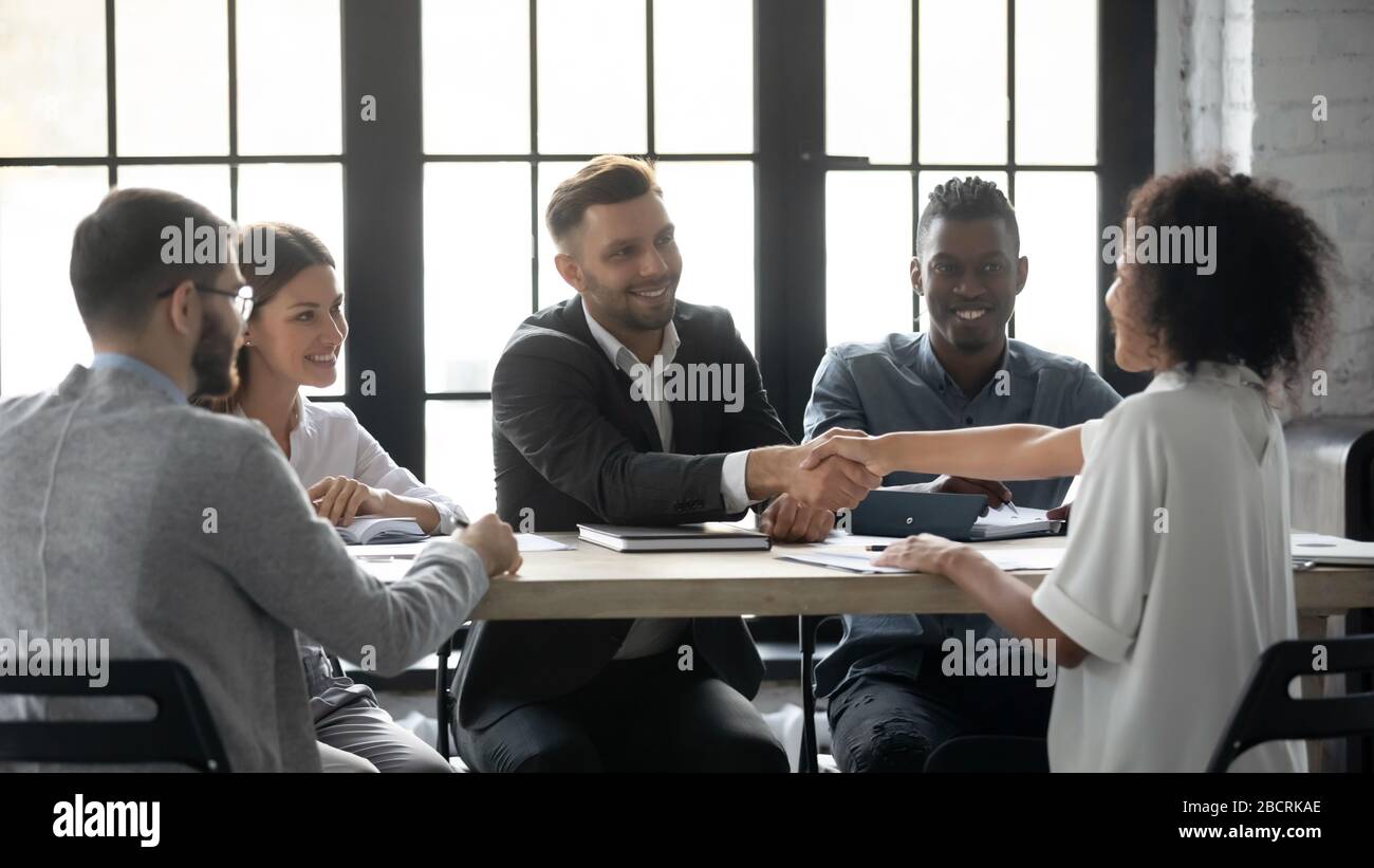 Erfolgreicher Geschäftsmann im Anzug, der die Hand der afroamerikanischen Geschäftsfrau schüttelt. Stockfoto