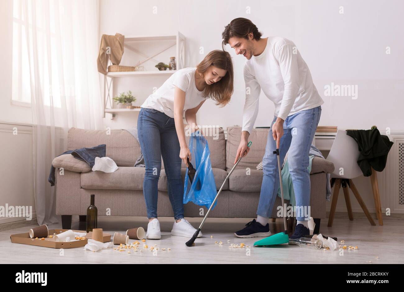 Paar Reinigung Unordentliche Zimmer Nach Party, Durchziehender Boden Und Müllabfuhr Stockfoto