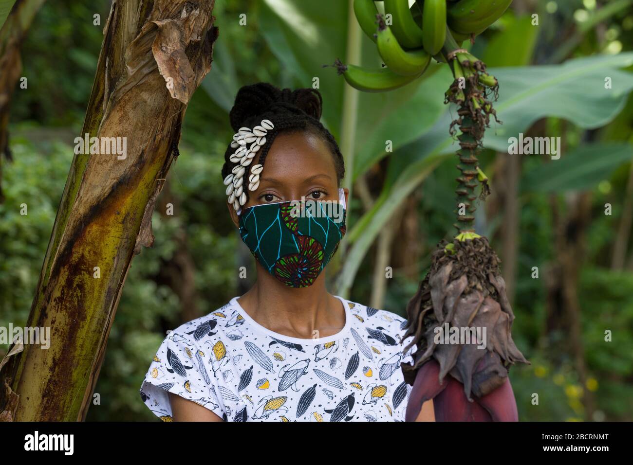 Eine kenianische Frau, die eine hausgemachte Maske trägt, aus traditionellem Kanga-Stoff zum Schutz vor einer Kovid-19-Pandemie. Chirurgische Masken befinden sich in kurzer Sup Stockfoto
