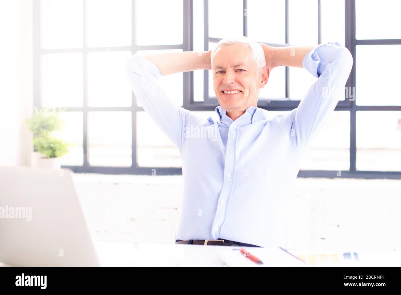 Schuss eines lächelnden zufriedenen Mannes, der während der Arbeit am Laptop zuhause im Stuhl ruht. Heimbüro. Stockfoto