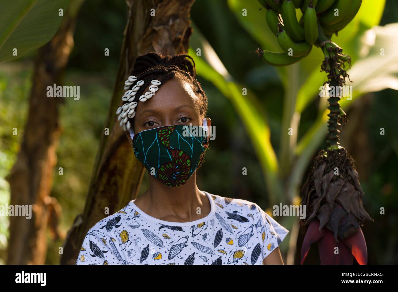 Eine kenianische Frau, die eine hausgemachte Maske trägt, aus traditionellem Kanga-Stoff zum Schutz vor einer Kovid-19-Pandemie. Chirurgische Masken befinden sich in kurzer Sup Stockfoto