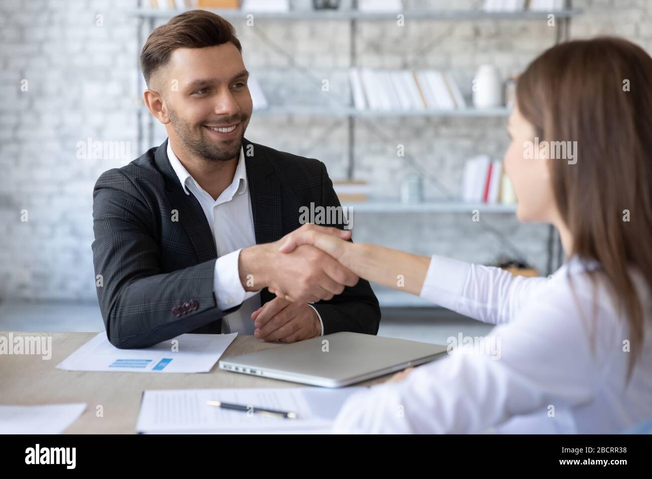 Glücklicher Geschäftsmann schüttelt die Hände mit Frau Arbeitssucherin im Anzug. Stockfoto
