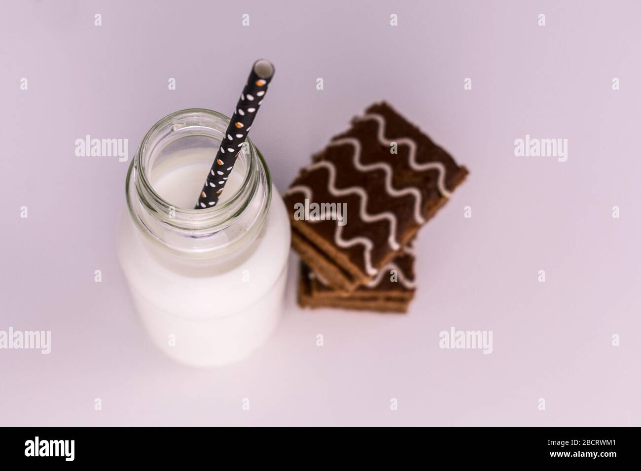 Flasche Milch und Schokoladenkuchen auf weißem Hintergrund. Ansicht von oben. Stockfoto