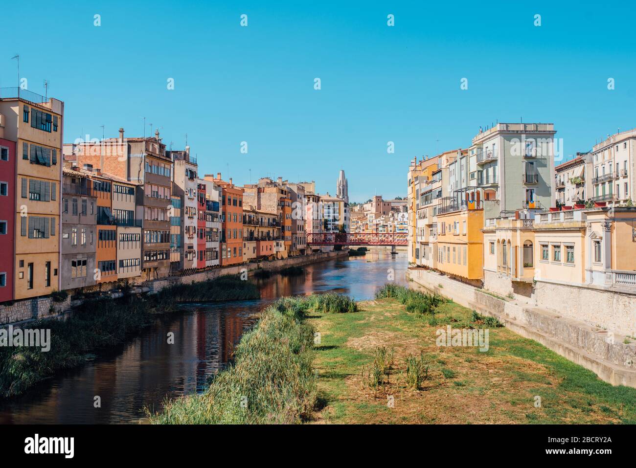 Farbenfrohe gelbe und orangefarbene Häuser und Brücke Pont de Sant Agusti spiegelten sich im Fluss Onyar in Girona, Katalonien, Spanien, wider. Kirche von Sant Feliu und Stockfoto