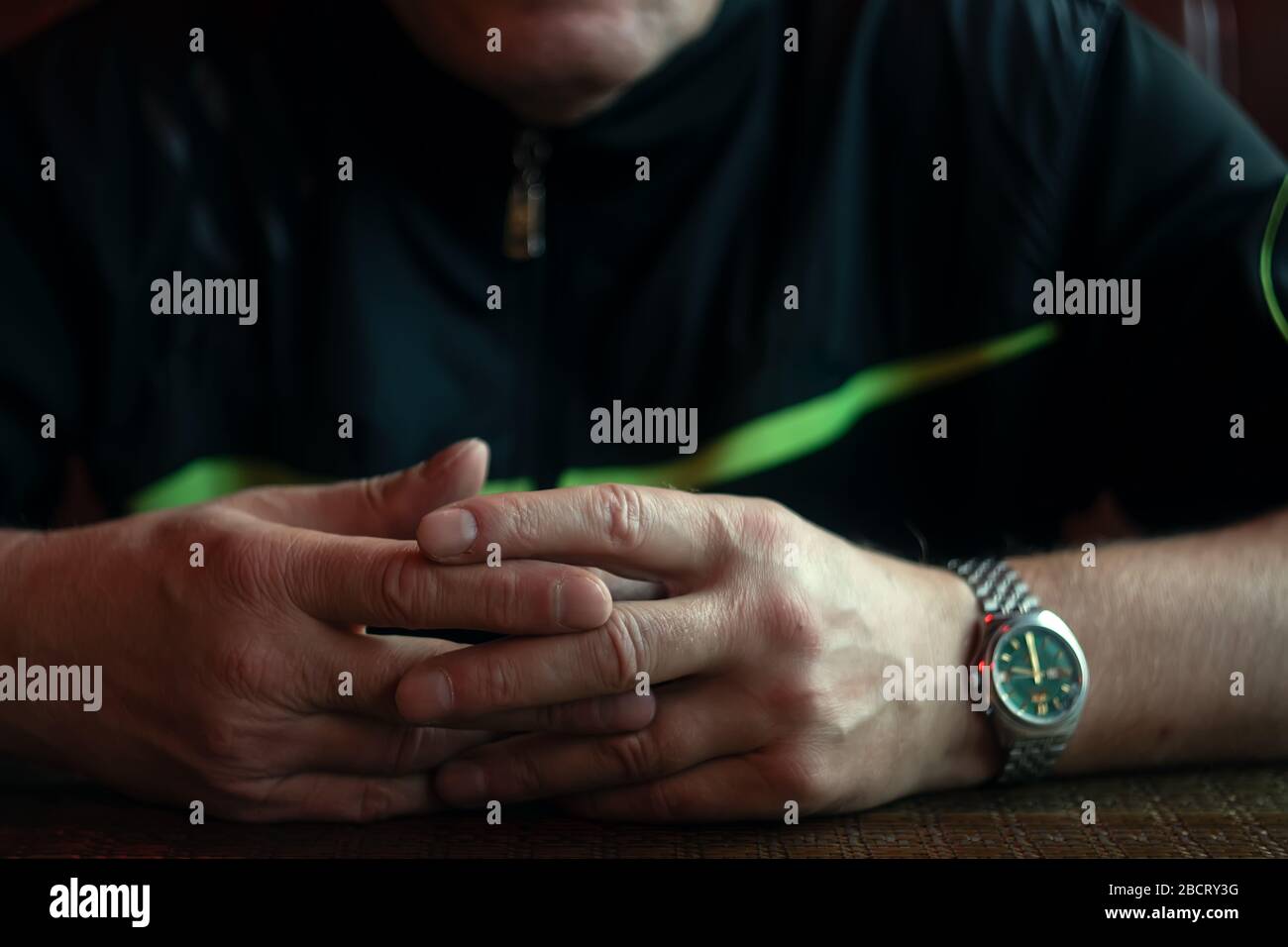 Hände eines alten Mannes mit Uhren auf dem Holztisch, Daumen mit Falten Stockfoto