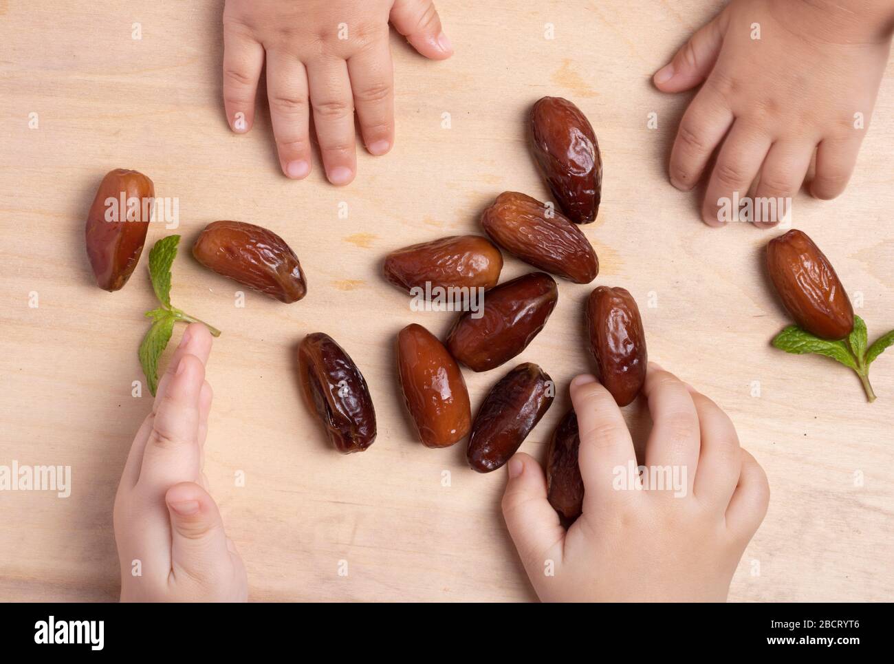 Kinder essen Datteln mit Minze, flacher Lay. Muslimisches fest am heiligen Monat des Ramadan-Konzepts. Stockfoto