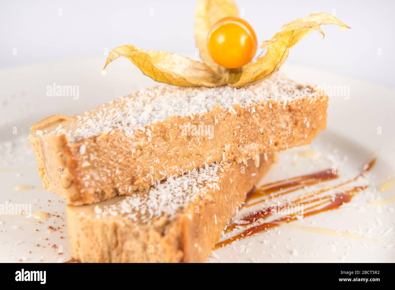 Dulce de leche und Kokosnussflaschendessert, dekoriert mit einer Physalis. Stockfoto