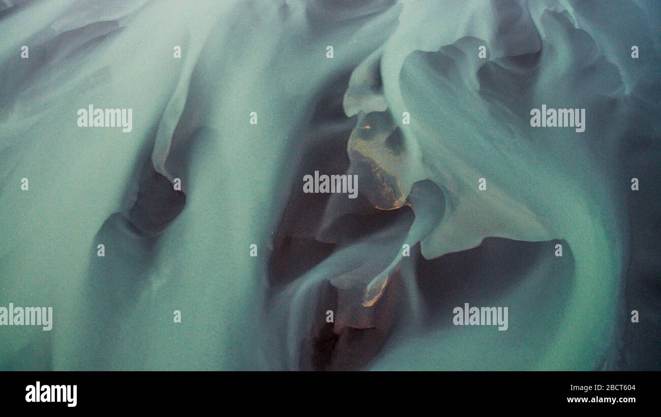 Vogelperspektive von oben auf einem grünen und blauen Gletscherfluss in Südisland. Schöne Muster, Texturen und Strukturen. Schmelzgletscher, GL Stockfoto