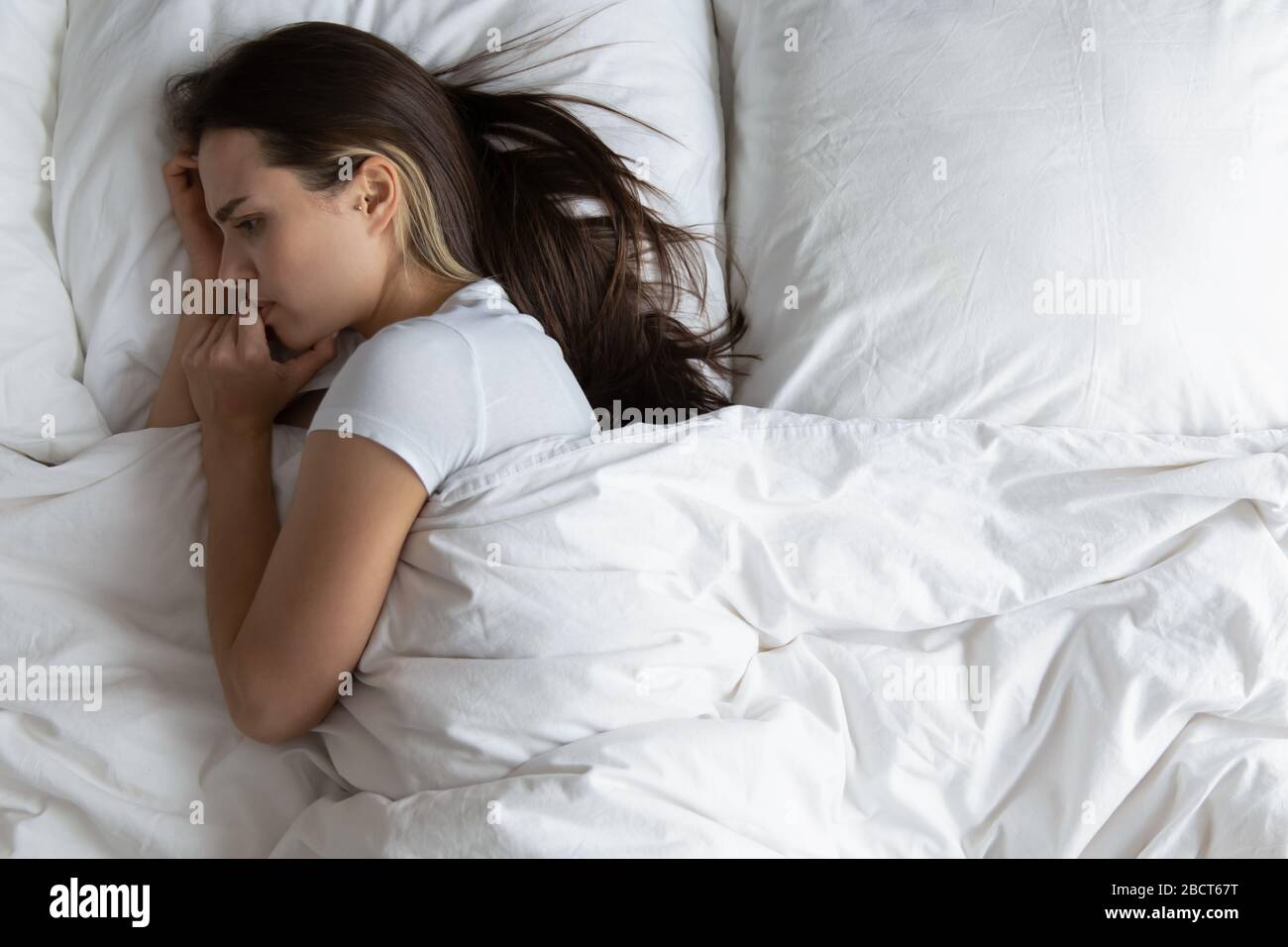 Ängstliche junge Frau, die sich im Bett erholt und einsam fühlt Stockfoto