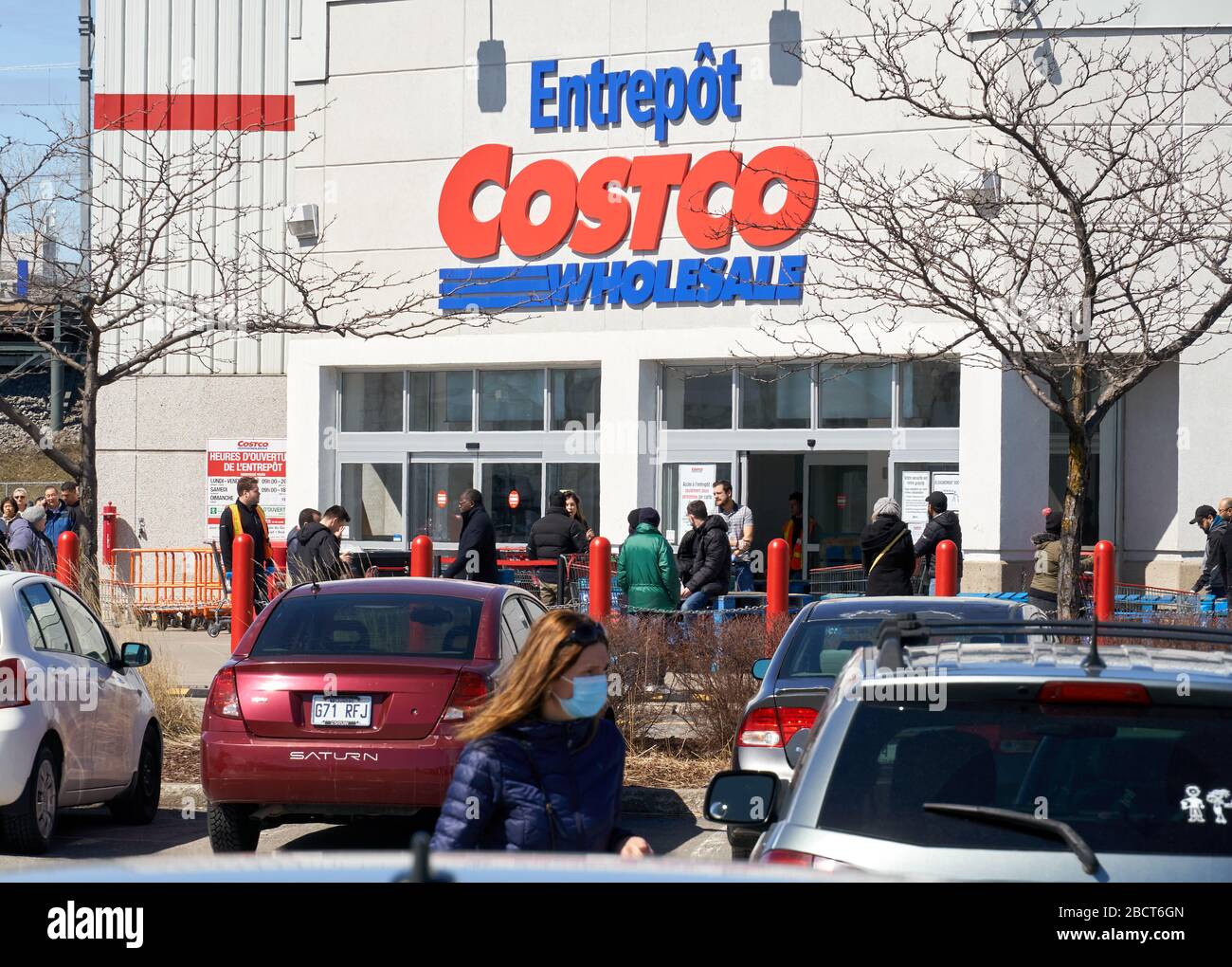 Montreal, Kanada - 4. April. 2020: Menschen mit Masken in einer Linie, um Costco Großhandel zu betreten. Viele Geschäfte führten soziale Distanzierungen durch, die zu Linien führten Stockfoto