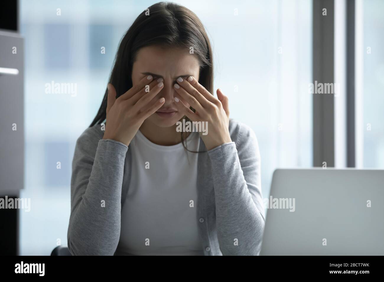 Erschöpfte weibliche Angestellte leiden unter Kopfschmerzen am Arbeitsplatz Stockfoto