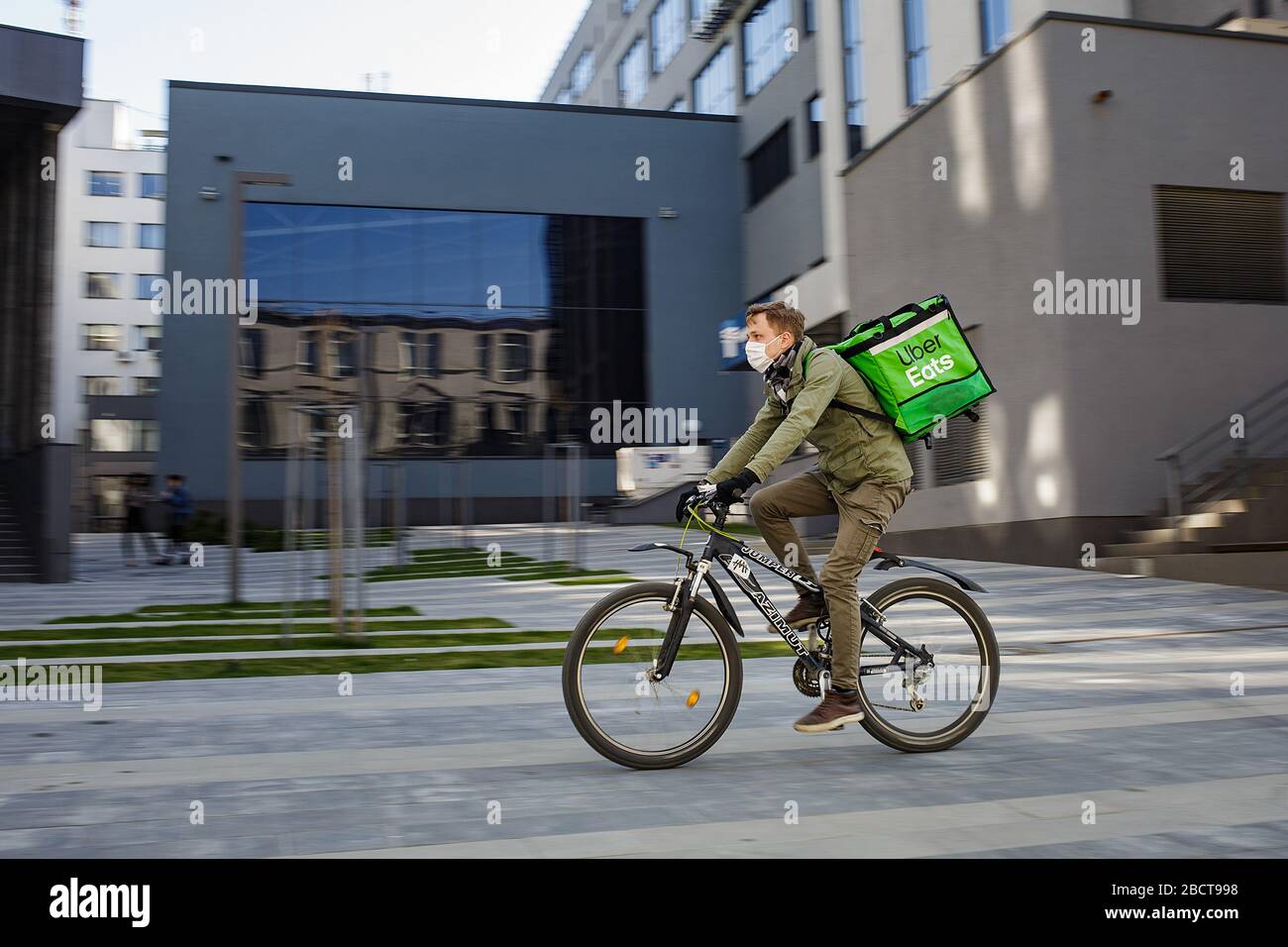 Lebensmittelzulieferer mit Uber isst Rucksack beim Fahrradfahren auf dem Stechen Stockfoto