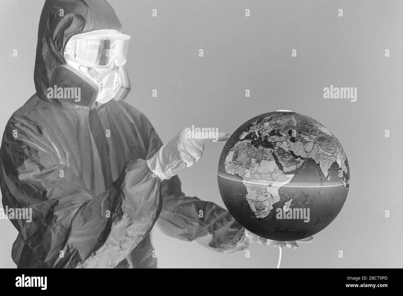 Konzept: Weltweite Viruskrise. Frau mit Laborkittel, Nitrilhandschuhen, Schutzbrille, Gesichtsmaske und NBC-Anzug für Covid-19 Coronavirus, zu Hause. Negatives Bild. Stockfoto