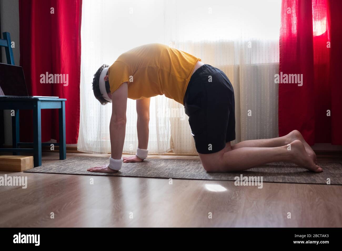 Junger Mann zu Hause trainieren, Yoga, Pilates, Fitness-Training, in Cat Yoga Pose Stockfoto