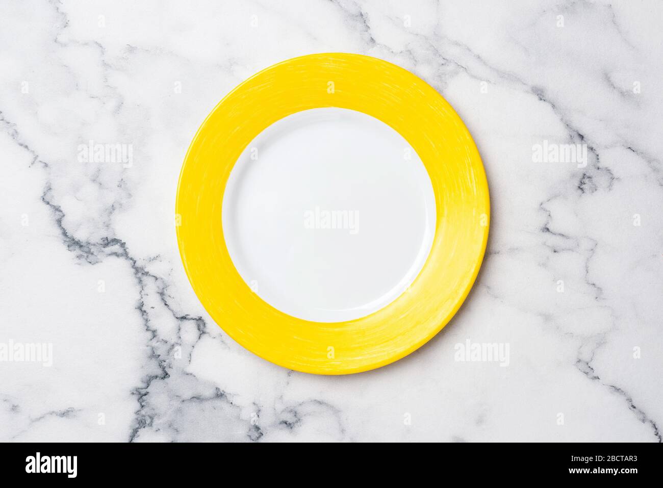 Leere Gelbe Platte Auf Marmorhintergrund. Obere Ansicht Kopierbereich für Text oder Design. Tischeinstellung Stockfoto