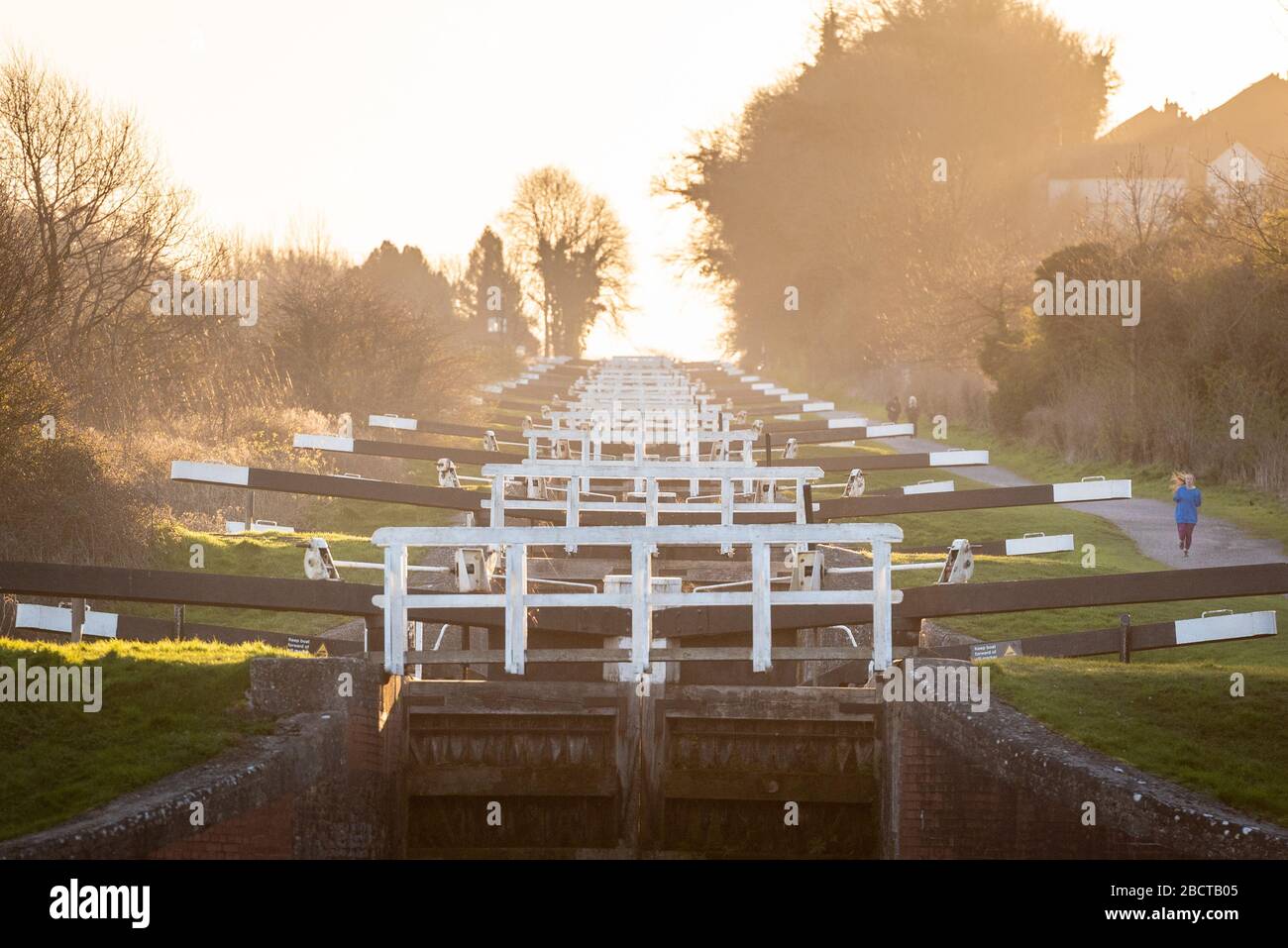 Caen Hill sperrt, in der Nähe von Devizes, Wiltshire, Großbritannien. März 2020. An einem knackigen Frühlingmorgen macht sich eine Läuferin auf den Weg entlang des Kennet- und Avon-Kanals und PA Stockfoto