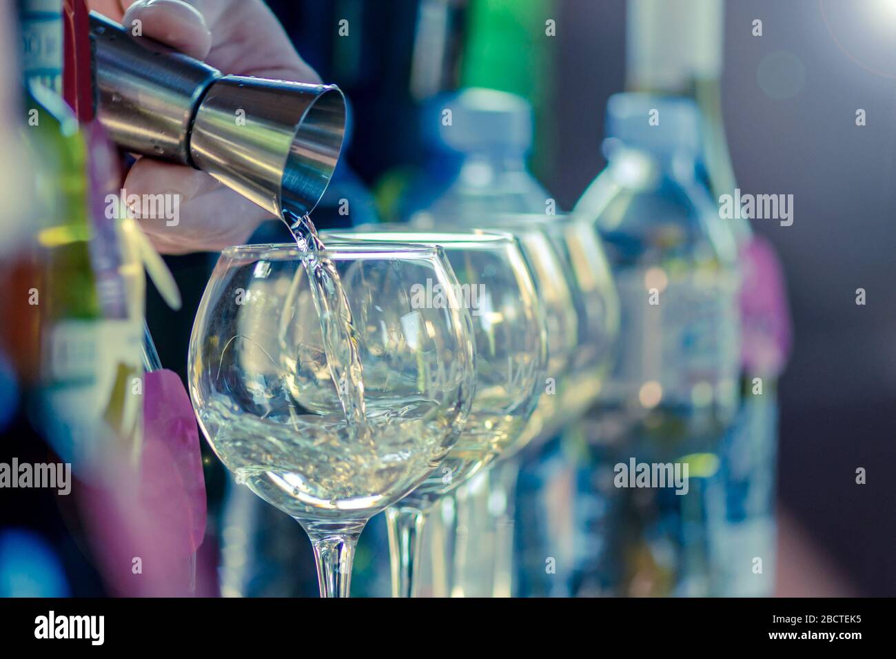 Die Hand des Barkeepers gießt mit Hilfe eines Spenders ein alkoholisches Getränk in ein Glas mit Eis. Starker Alkohol Stockfoto