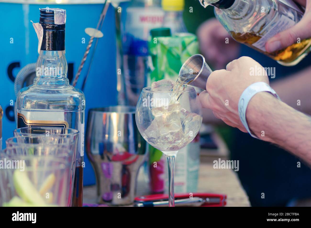 Die Hände des Barkeepers gießen ein starkes alkoholisches Getränk in ein Glas mit Eis. bourbon, Rum, Tequila Stockfoto