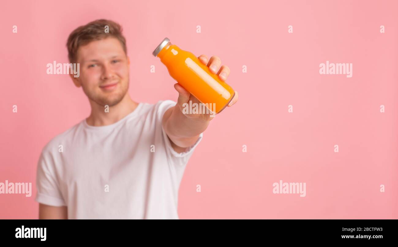 Junger Mann, der eine Glasflasche mit Vitamingetränk hält, um die Immunität zu erhöhen Stockfoto