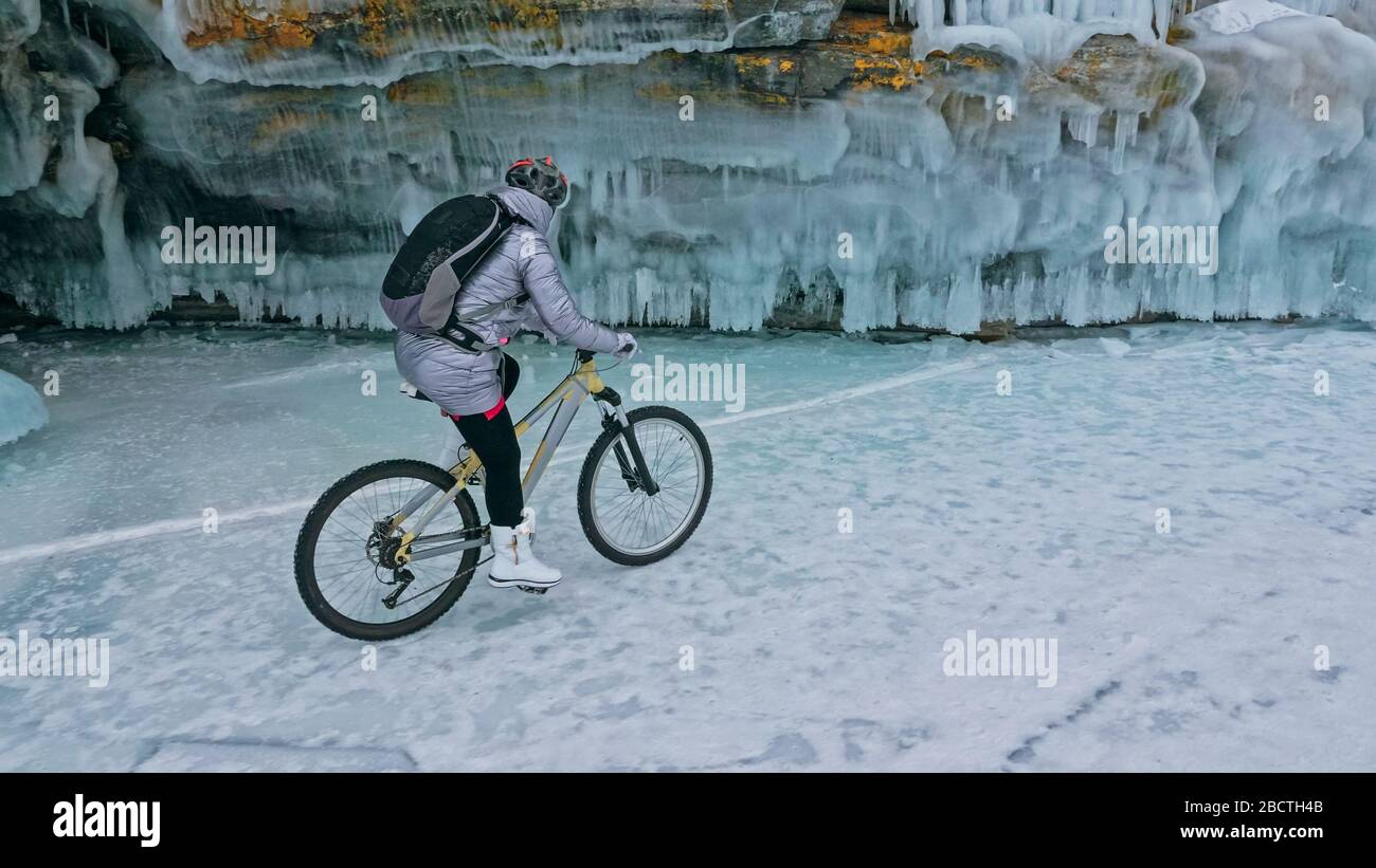 Frau fährt Fahrrad in der Nähe der Eisgrotte. Der Felsen mit Eis c Stockfoto