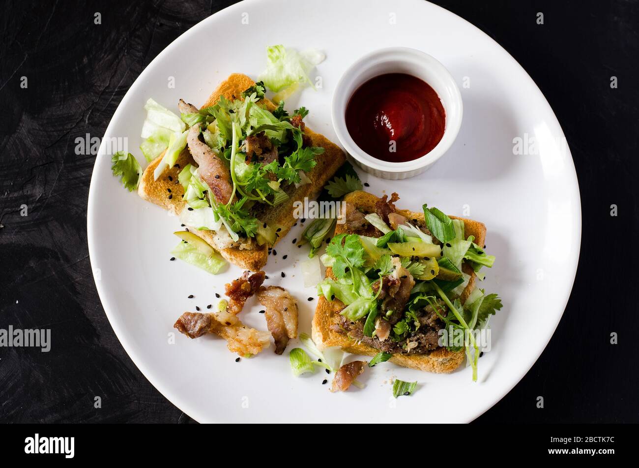 Toasts mit gegrilltem Schweinefleisch, Gemüse, Koriander und Sriracha-Sauce Stockfoto