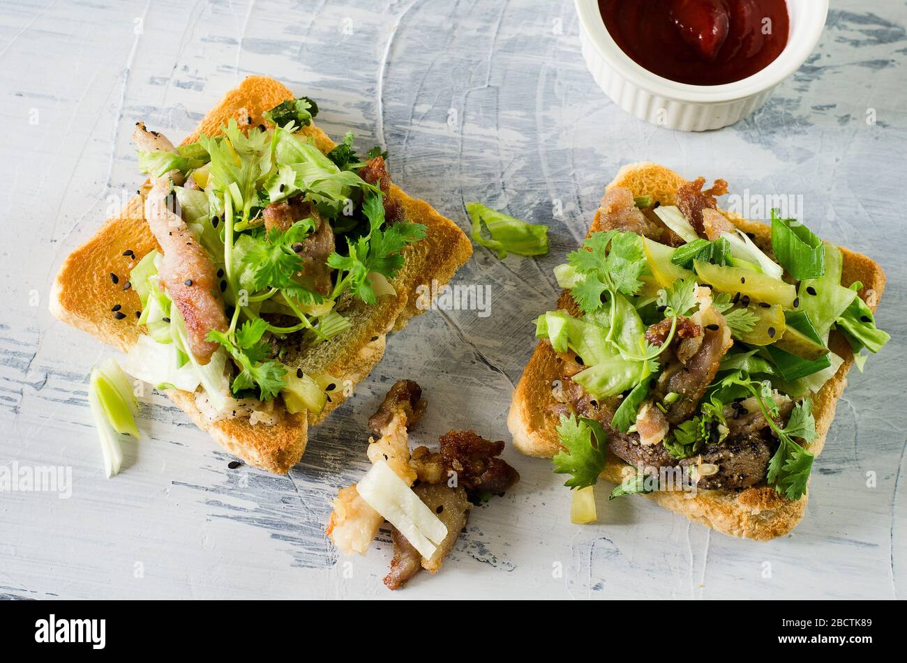 Toasts mit gegrilltem Schweinefleisch, Gemüse, Koriander und Sriracha-Sauce Stockfoto