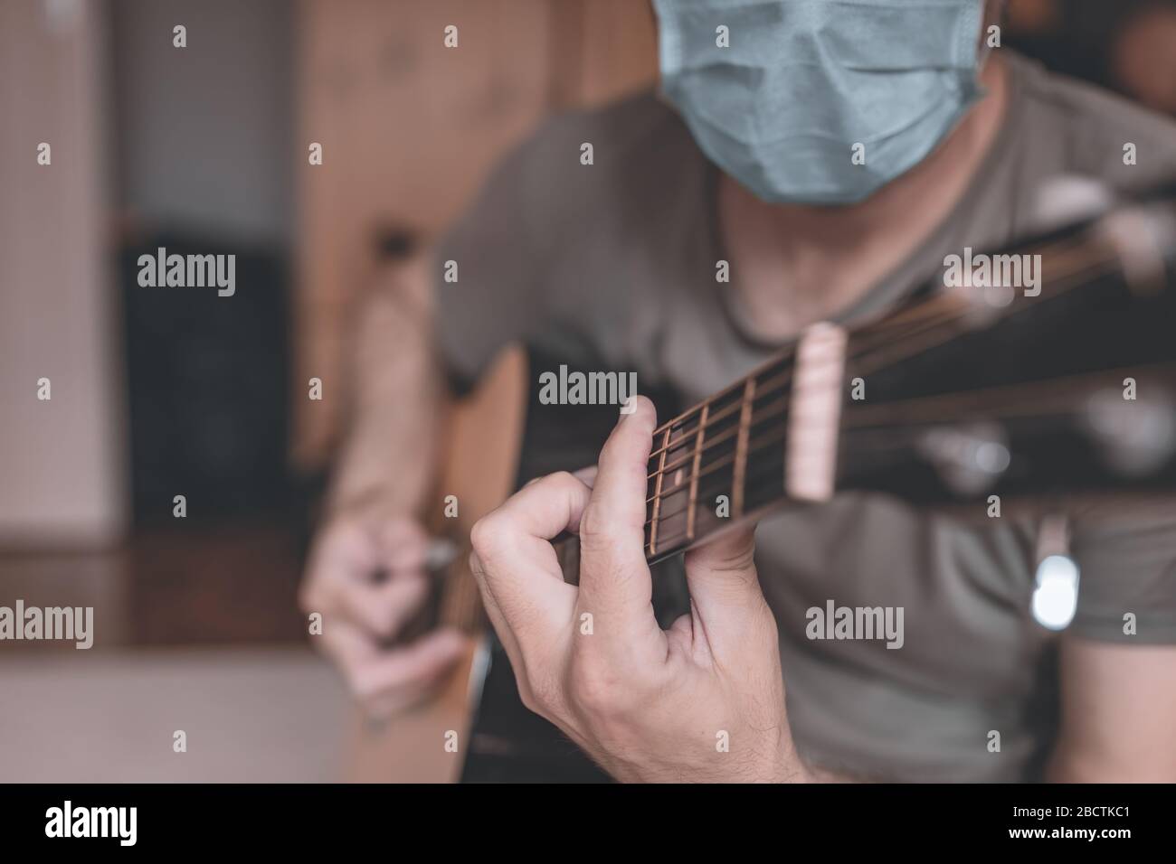 Mann, der zu Hause akustische Gitarre spielt, Quarantäne sich während des Covid-19-Coronavirus-Ausbruchs Stockfoto