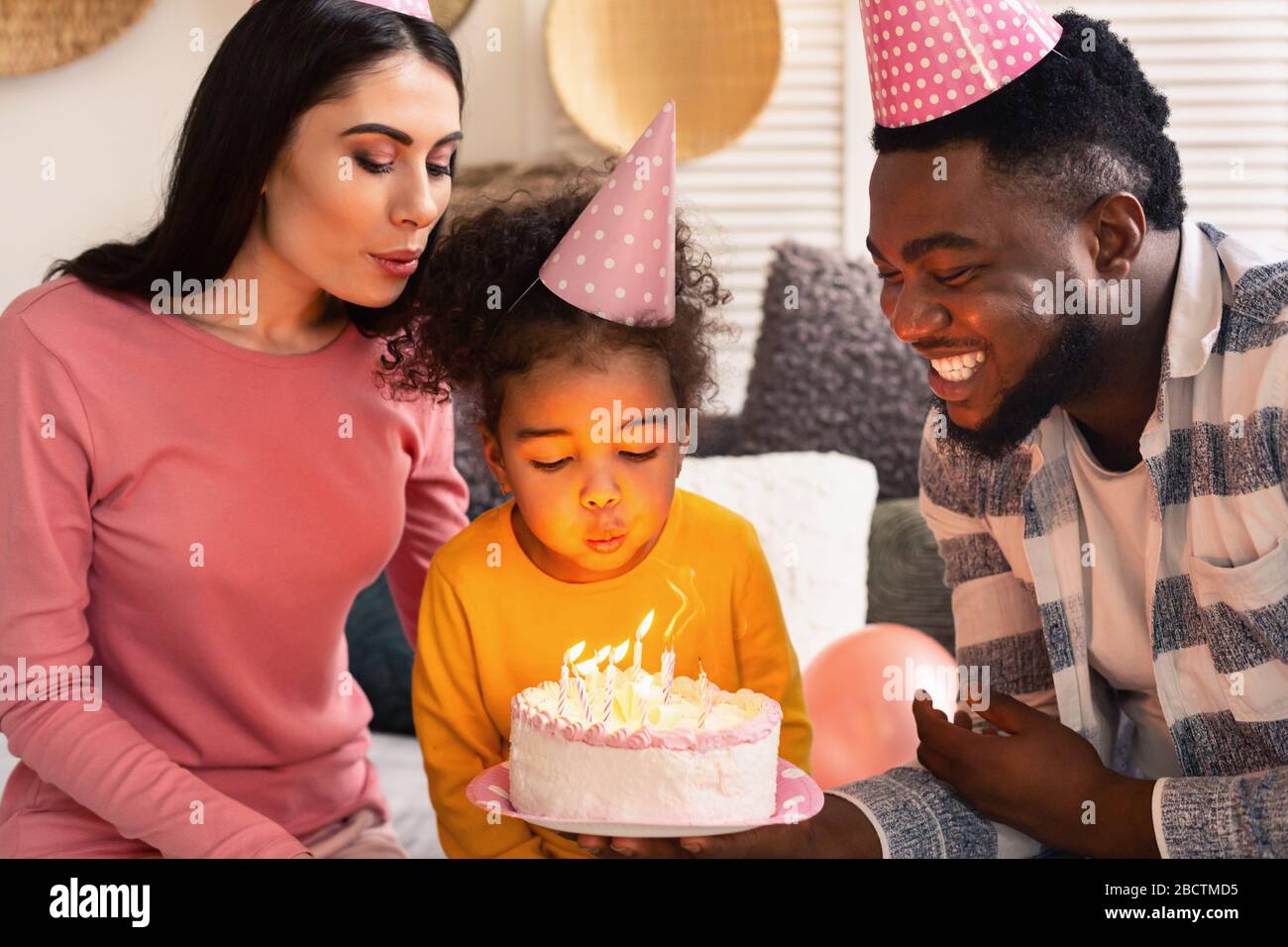 Familie bläst Kerzen auf einen Kuchen aus Stockfoto