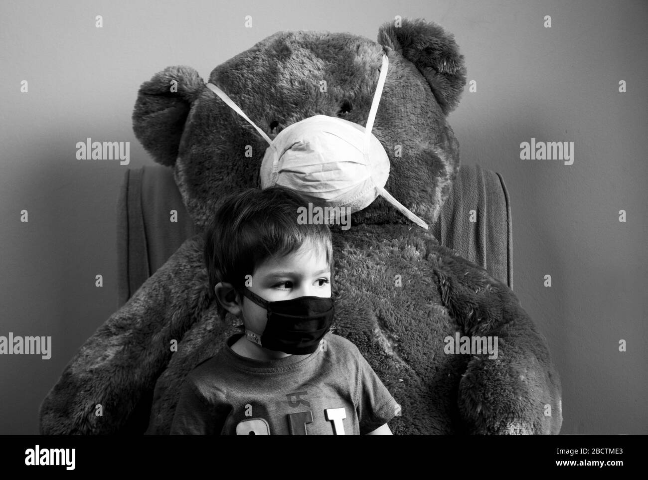 Coronavirus, Covid-19, Junge und sein Teddybär in Schutzmasken, Quarantäne zu Hause Stockfoto