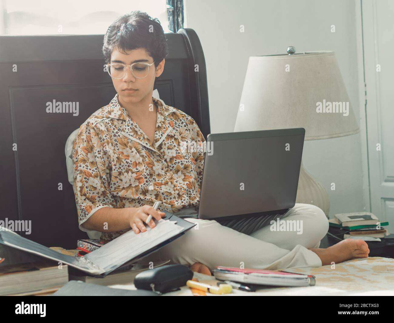 Frau, die von zu Hause aus arbeitet, einige Papiere überprüft und auf dem Laptop tippt Stockfoto