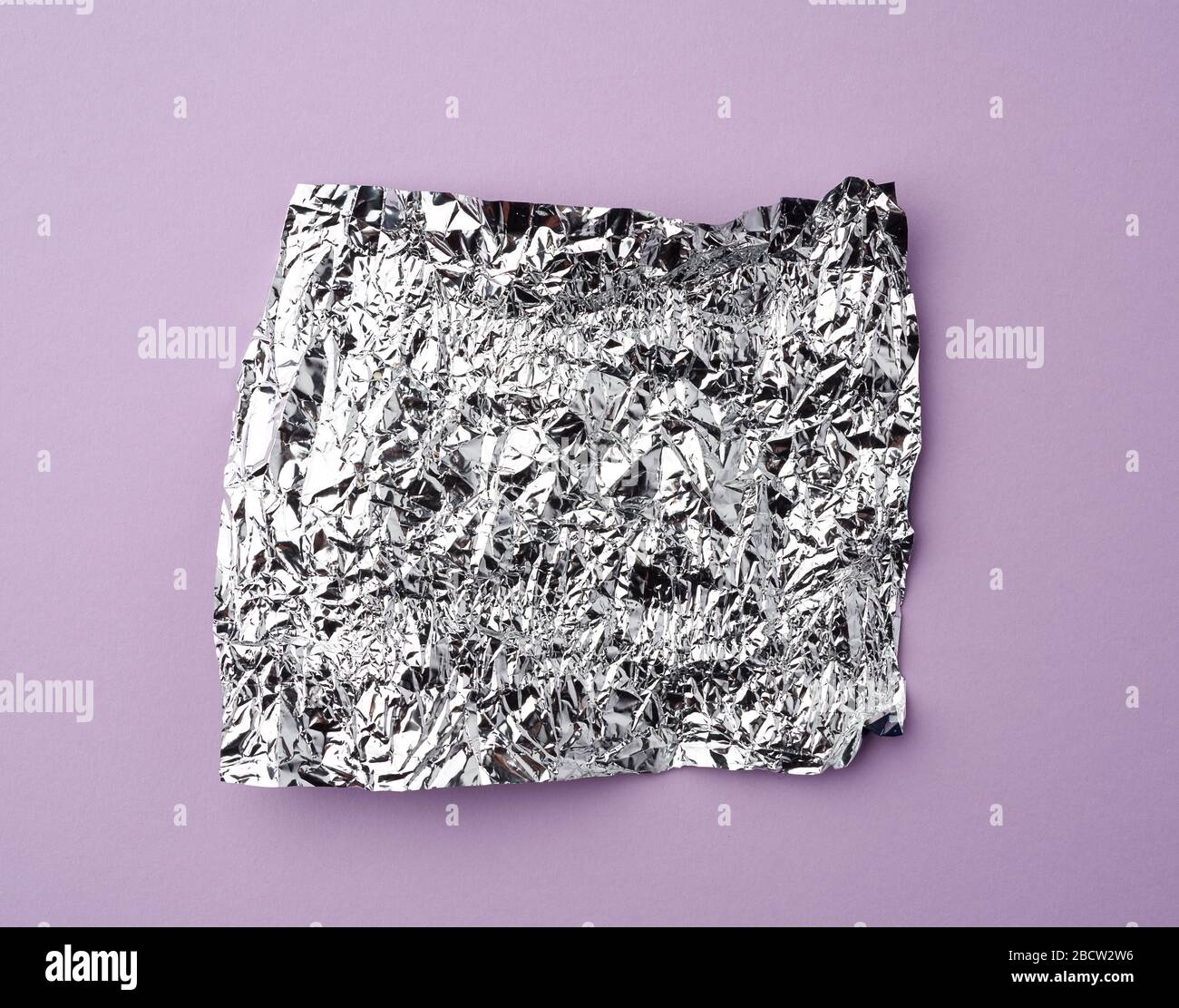 Zerknitterte Folie verwendete Süßigkeiten-Wrapper auf einem lilafarbenen Hintergrund, Draufsicht Stockfoto
