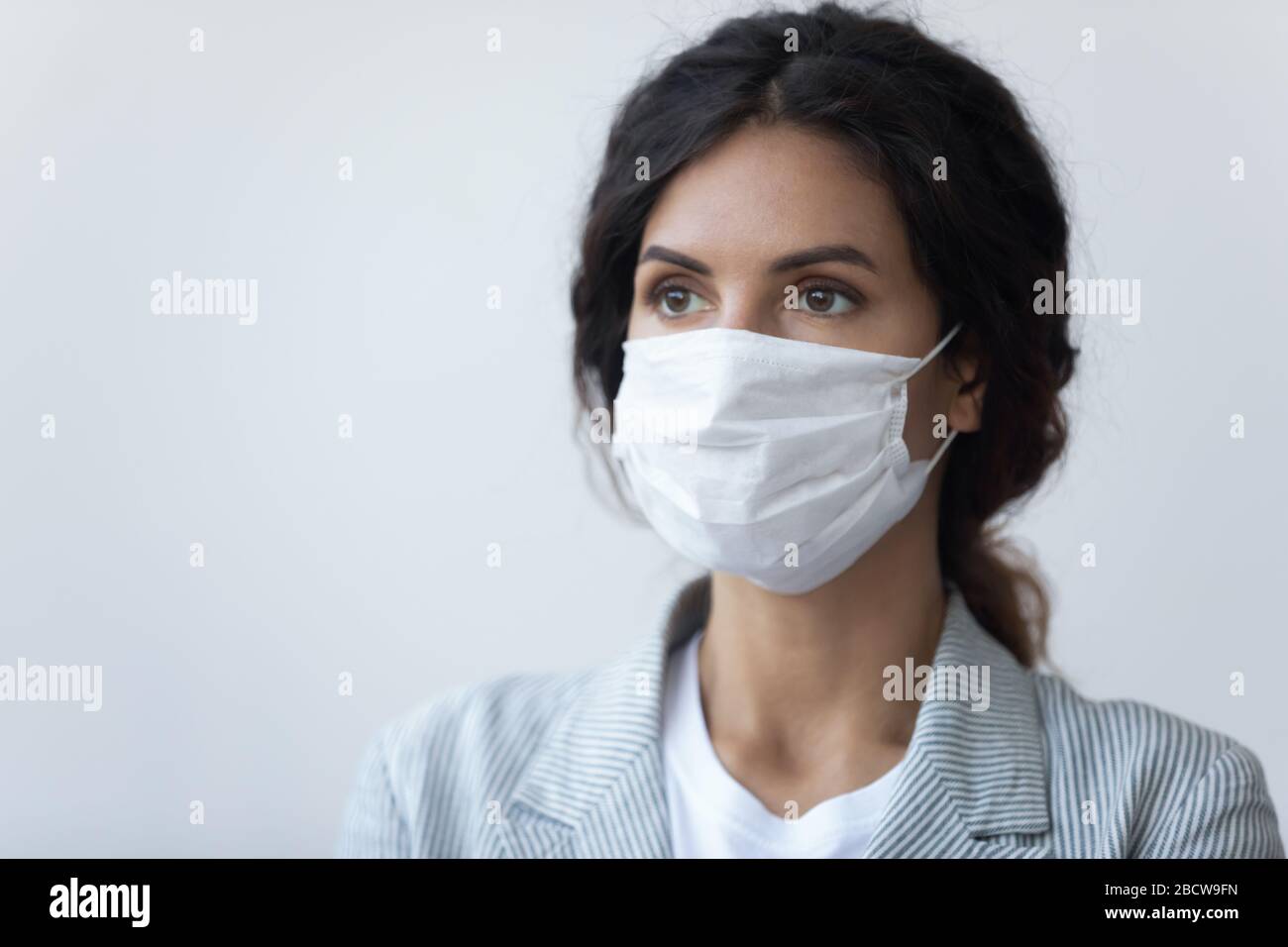 Ernste Dame, die medizinische Maske trägt und den Atem vor Luftverschmutzung schützt. Stockfoto