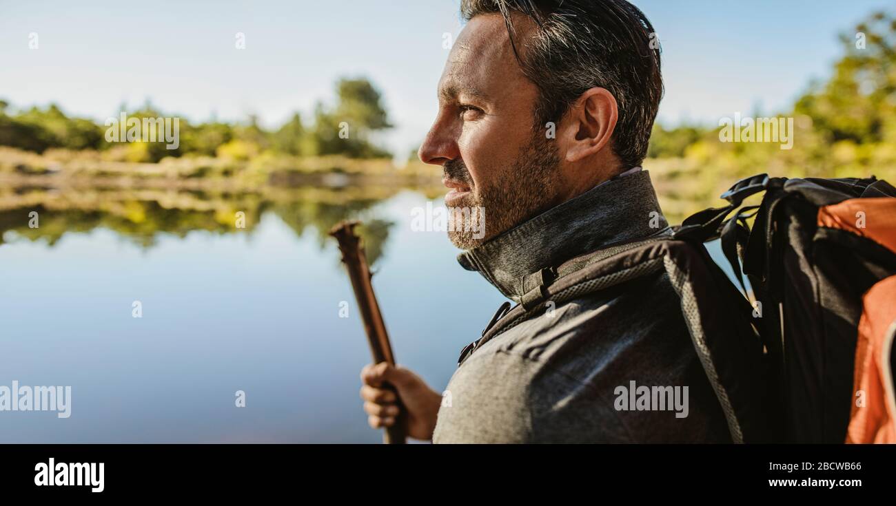 Nahaufnahme eines reifen Mannes mit Rucksack am See. Wohnmobil mit Blick auf die Aussicht. Stockfoto