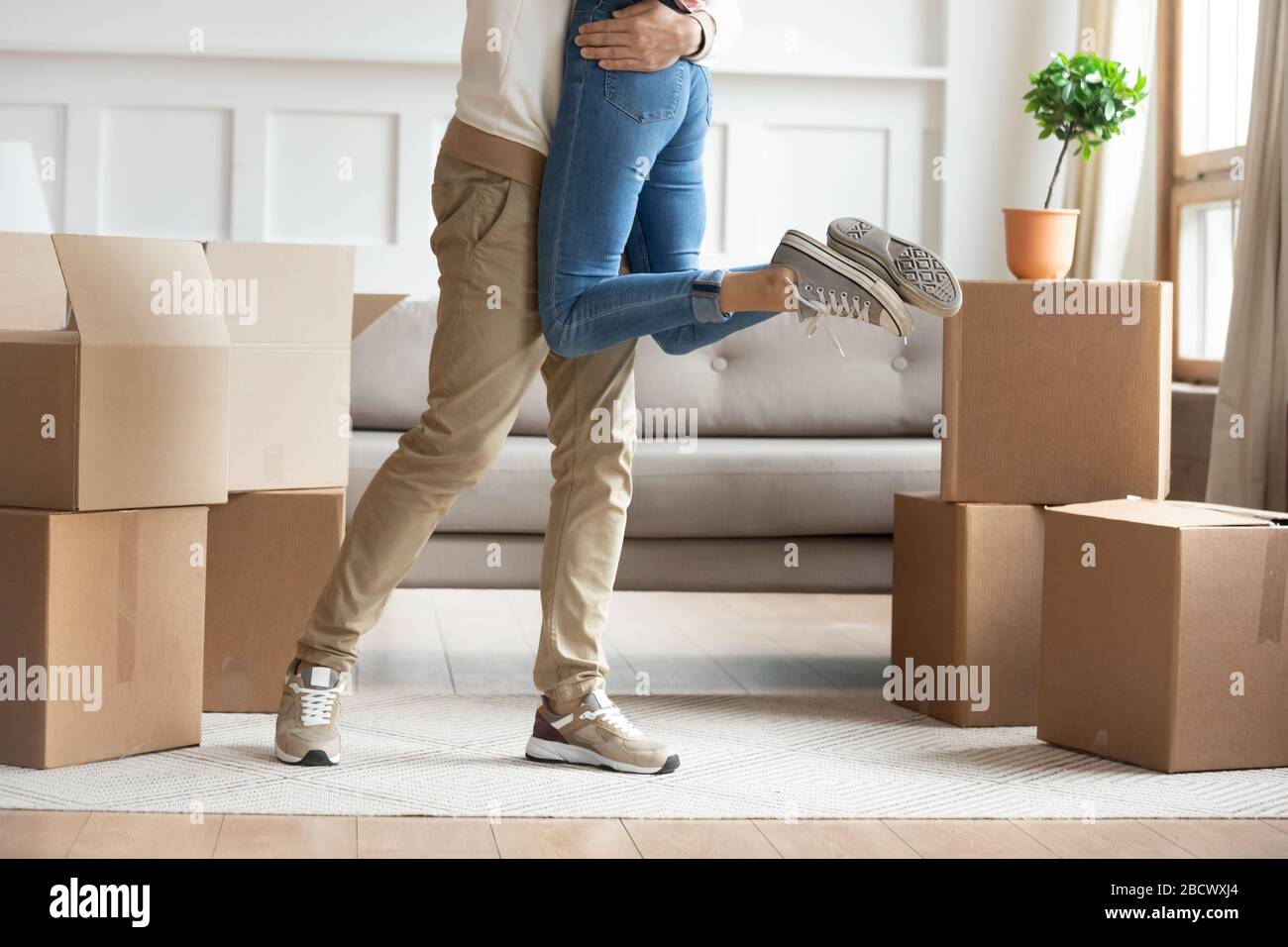 Zugeschnittenes Bild junger Mann, der die umarmende Frau hebt. Stockfoto