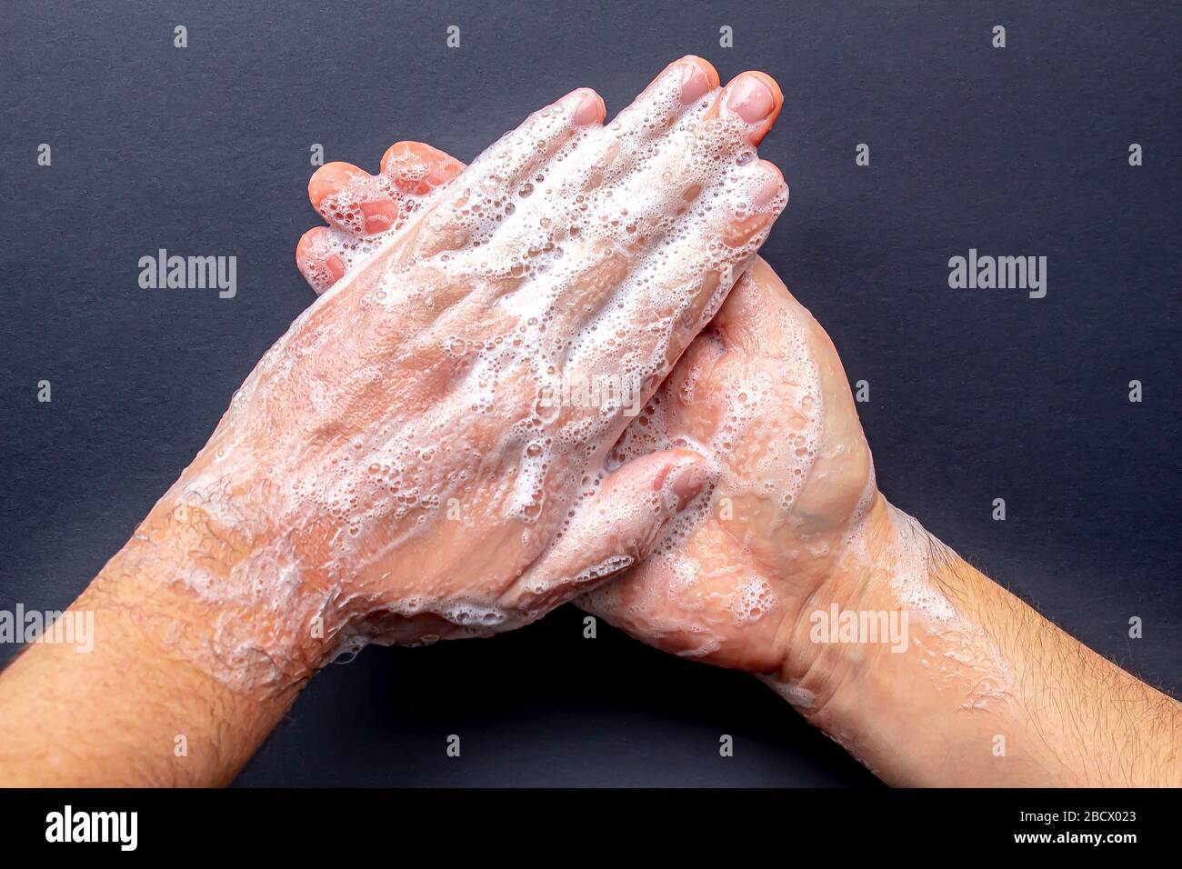 Eine Person, die die Hände mit Seife auf schwarzem Hintergrund waschen kann Stockfoto