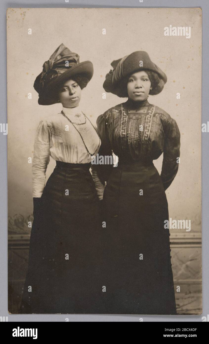 Fotografische Postkarte von Harriet Tubmans großen Nichten Eva und Alida Stewart. Eine fotografische Postkarte mit einem Schwarz-Weiß-Bild von Harriet Tubmans großen Nichten, Eva und Alida Stewart. Das durchgehende Porträt zeigt die beiden nebeneinander stehenden Frauen, die große Hüte mit langärmeligen Blusen und langen Röcken tragen. Fotografische Postkarte von Harriet Tubmans großen Nichten Eva und Alida Stewart Stockfoto