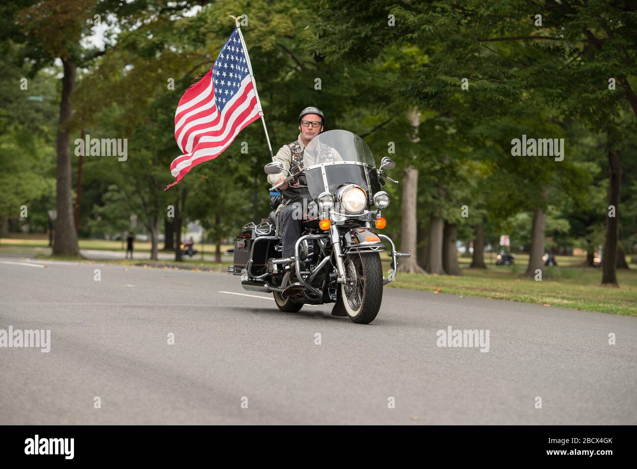 Ein Rolling Thunder Motorradfahrer mit einer großen amerikanischen Flagge auf der Rückseite des Fahrrads bei einer Vietnam Veterans Rallye. Stockfoto