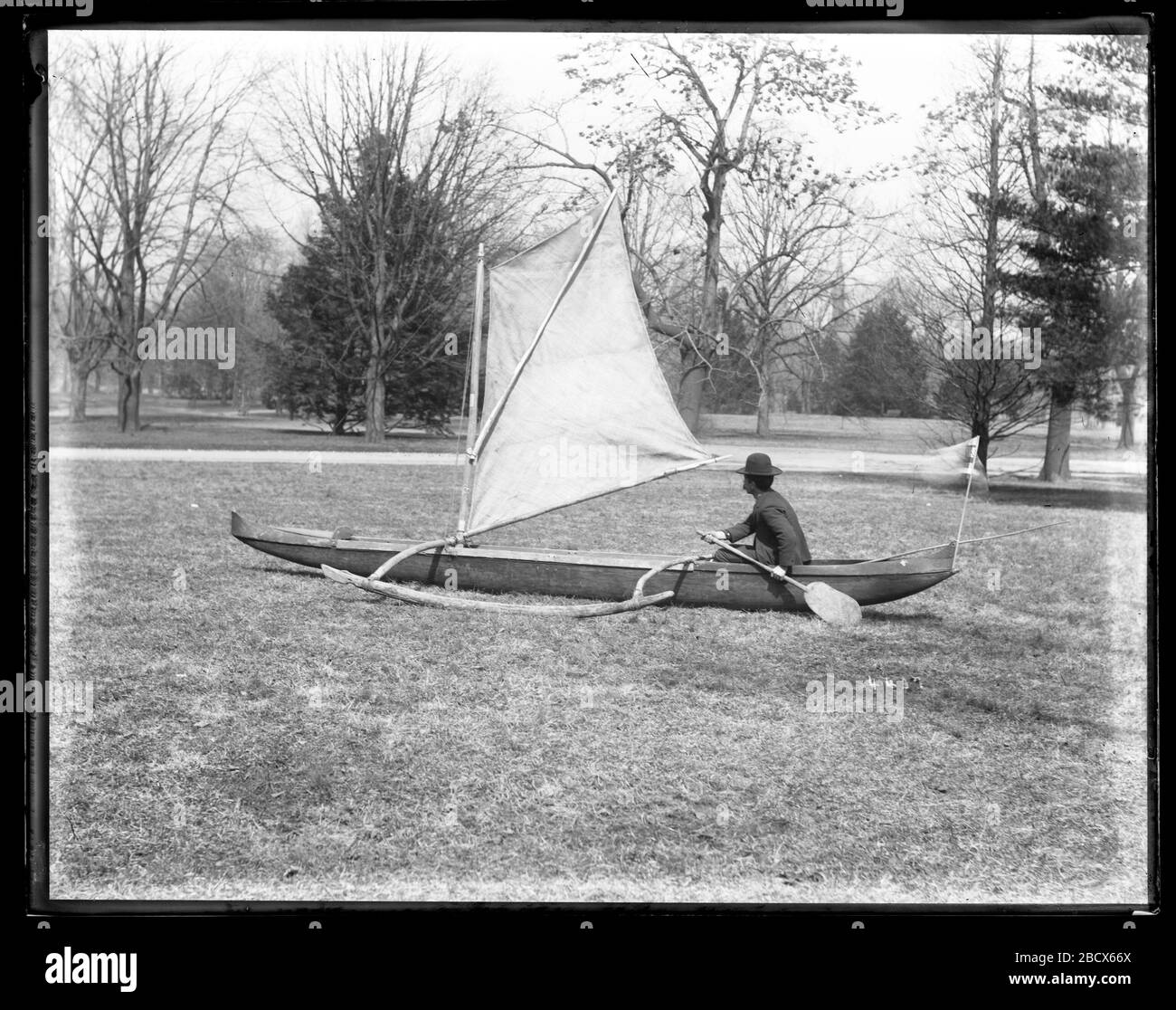 Outrigger Canoe auf dem Museumsgelände. Nicht identifizierter männlicher Mitarbeiter des United States National Museum demonstriert das Bemannen eines Segel-Auslegerkanus auf dem Museumsgelände.Smithsonian Institution Archives, ACC. 11-007, Box 020, Bild-Nr. MNH-4437 Stockfoto