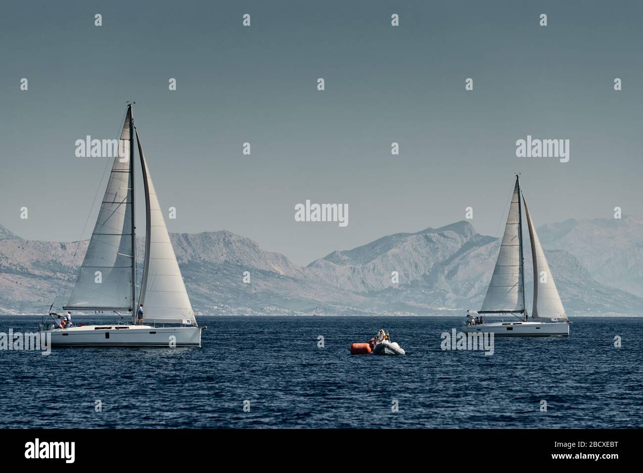 Das Gummiboot der Organisatoren einer Regatta mit dem Richter und dem Ballon von oranger Farbe, das Rennen der Segelboote, intensiver Wettbewerb, Insel mit Stockfoto