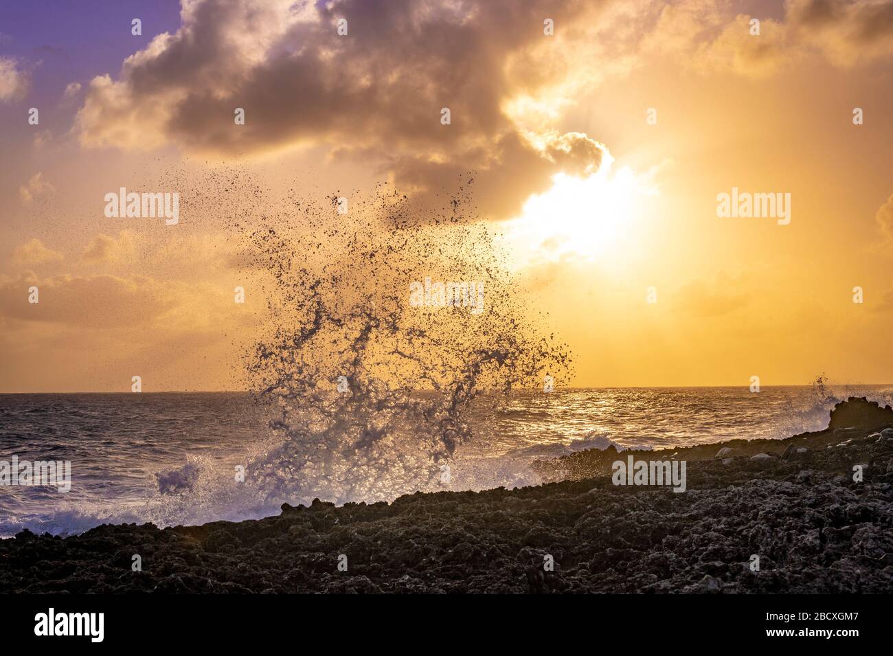 Große Wellen, die bei Sonnenuntergang gegen Felsen plätschern, Blowholes, Grand Cayman Island Stockfoto