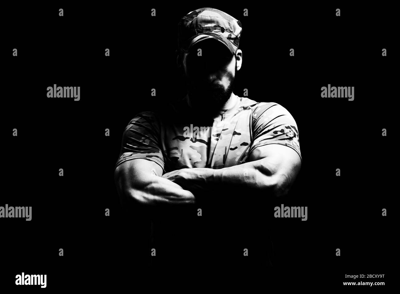 Porträt eines American Marine Corps Special Operations modern Warfare Soldier Arms gekreuzt mit Cap on Black Background Stockfoto