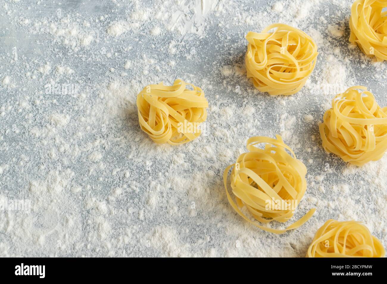 Handgemachte italienische Pasta - Tagliatelle auf grauem, florischem Hintergrund Stockfoto