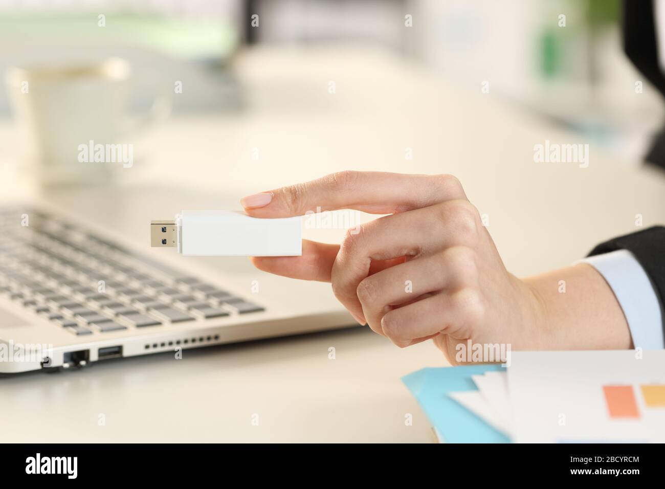 Nahaufnahme der Geschäftsfrau mit Laptop-Hand, die einen hängenden Stick im Büro zeigt Stockfoto